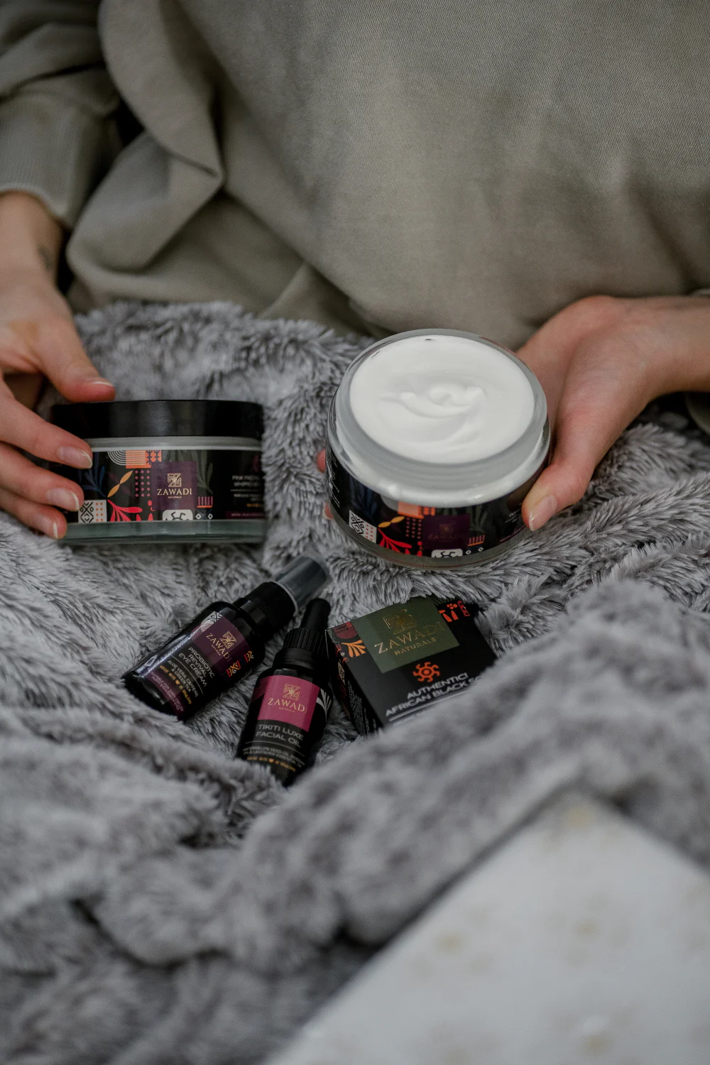 Pink Prestige whipped shea butter displayed with other skincare products on soft grey velvet fabric, styled as a luxurious self-care gift set.